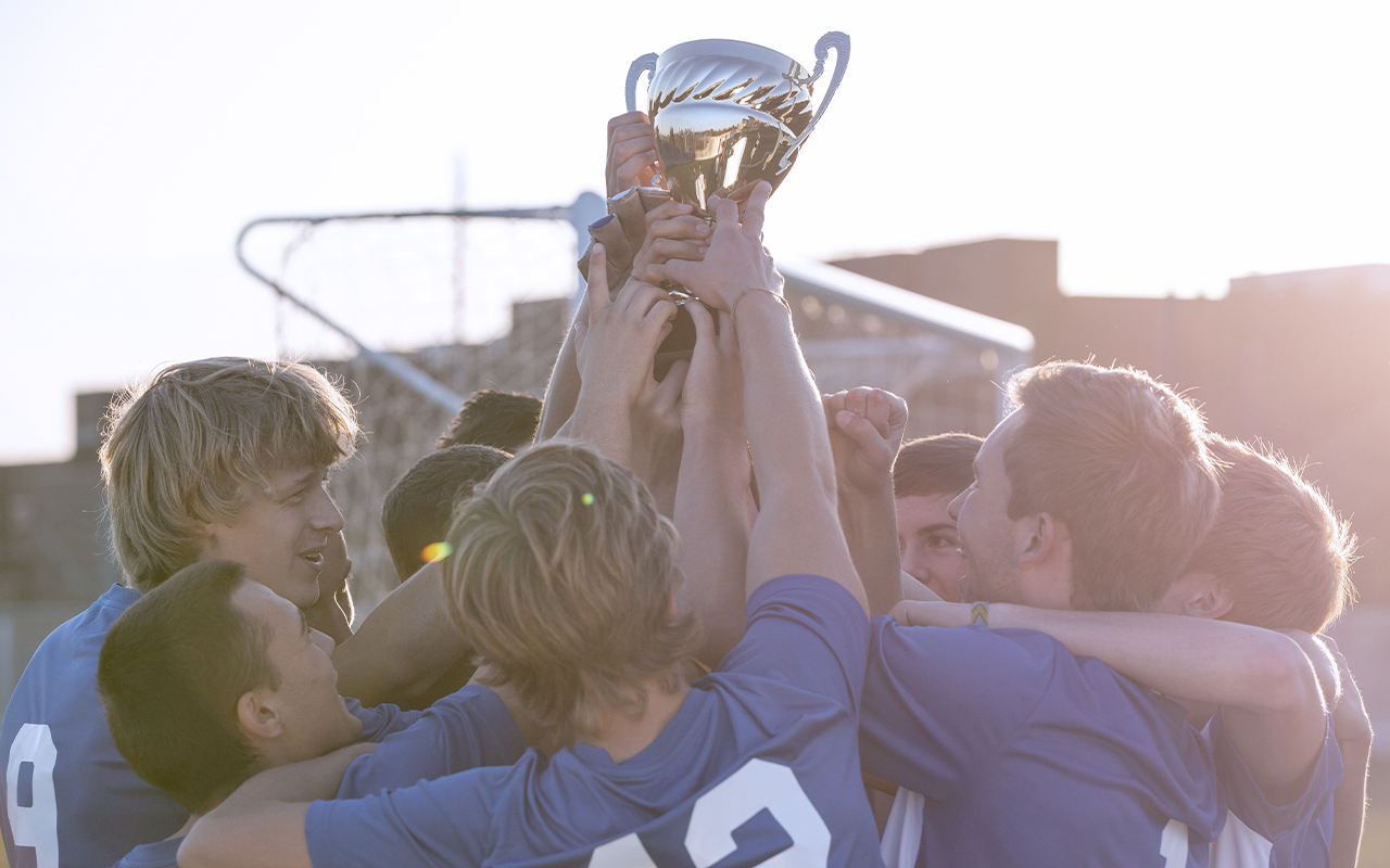 group of child sport players lifting a trophy in the air