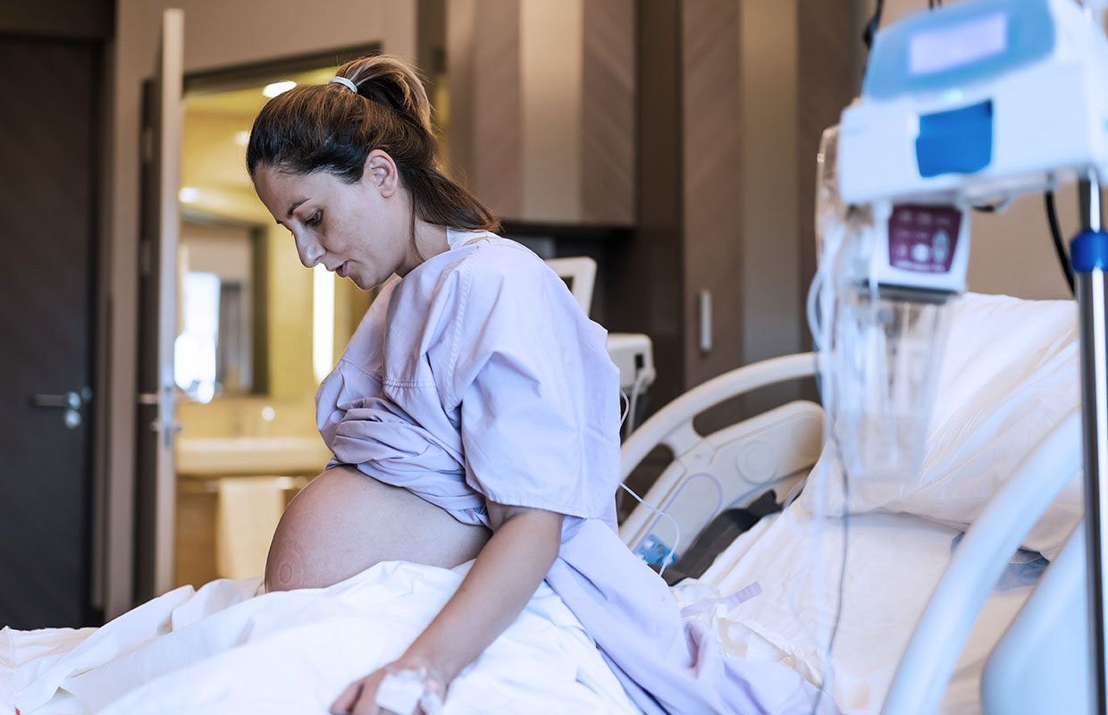 pregnant women in hospital bed looking down at stomach