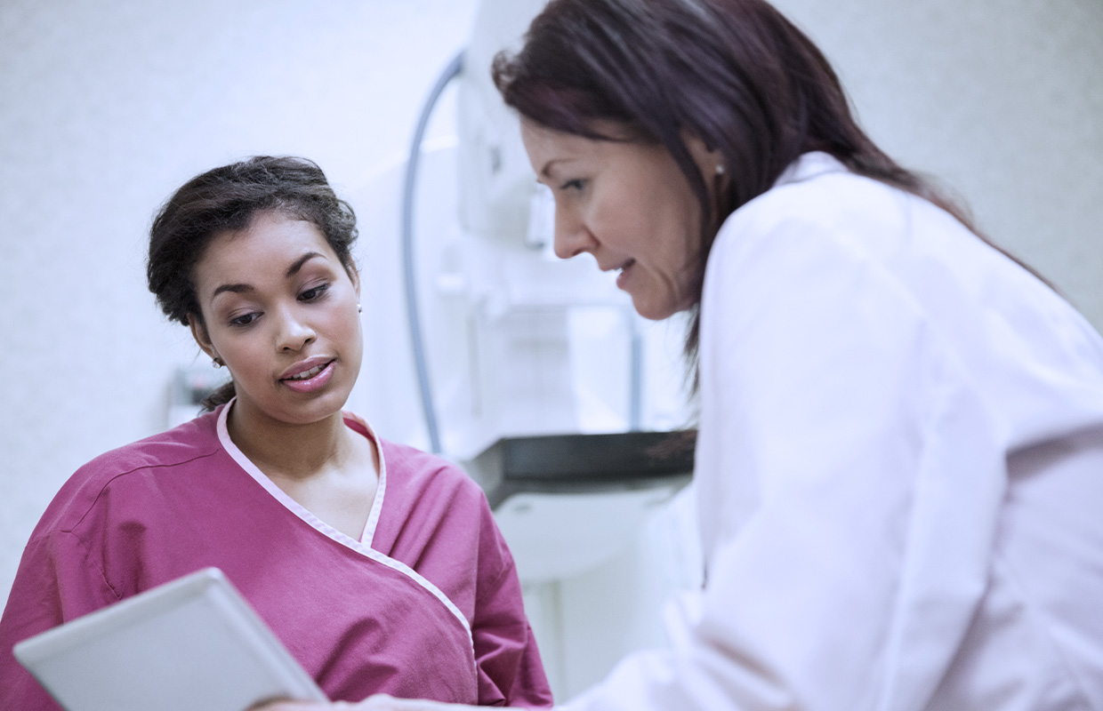 female in pink lead apron on exam table while female doctor explains test results