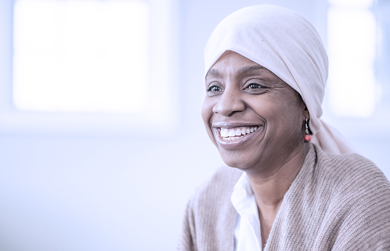 women in head wrap smiling during chemo treatment