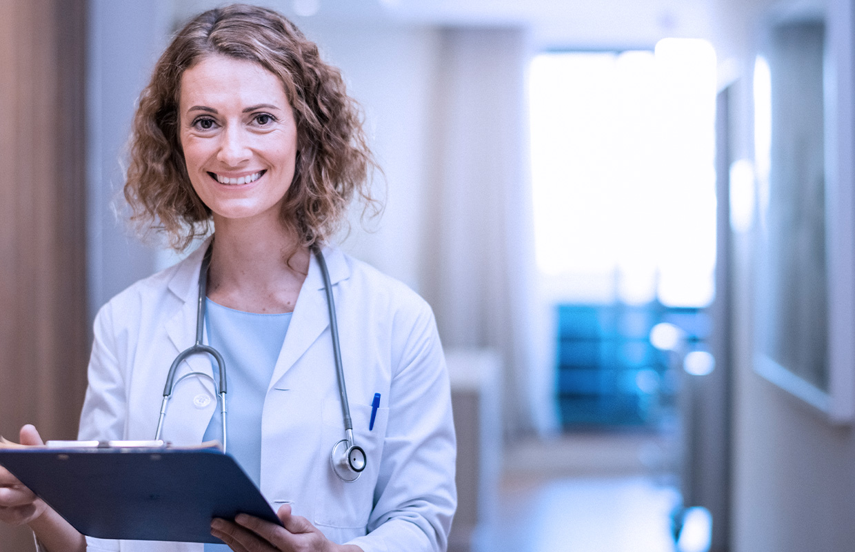 female physician stands with a clipboard outside of hospital room