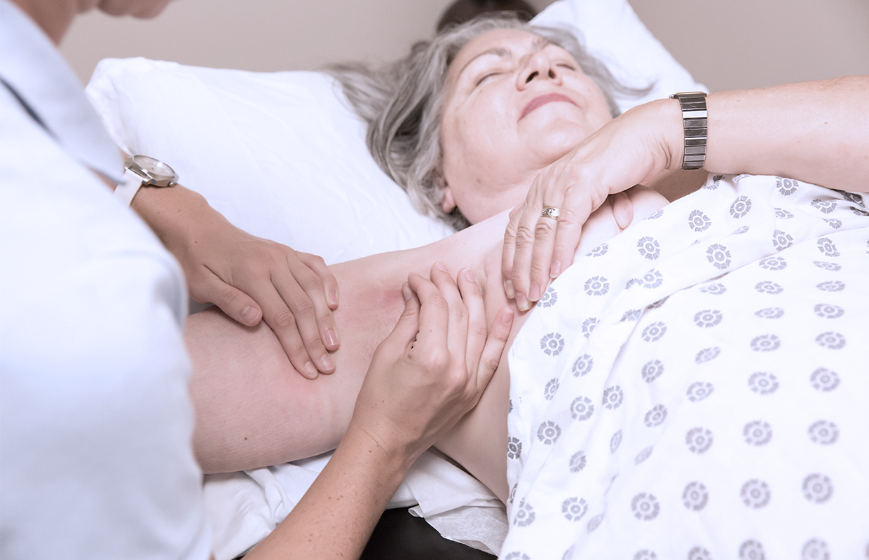 doctor feeling a swollen arm of a senior female patient