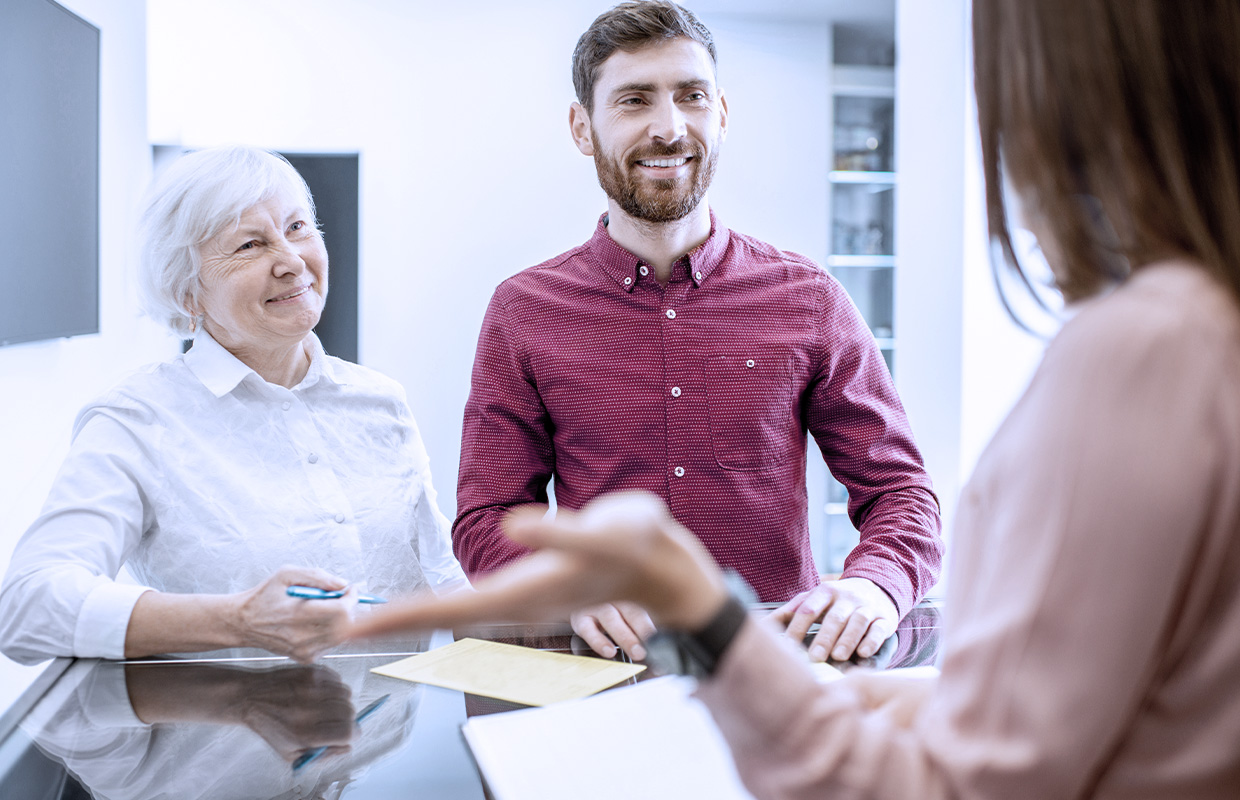 elderly female smiling with her middle age son at medical professional