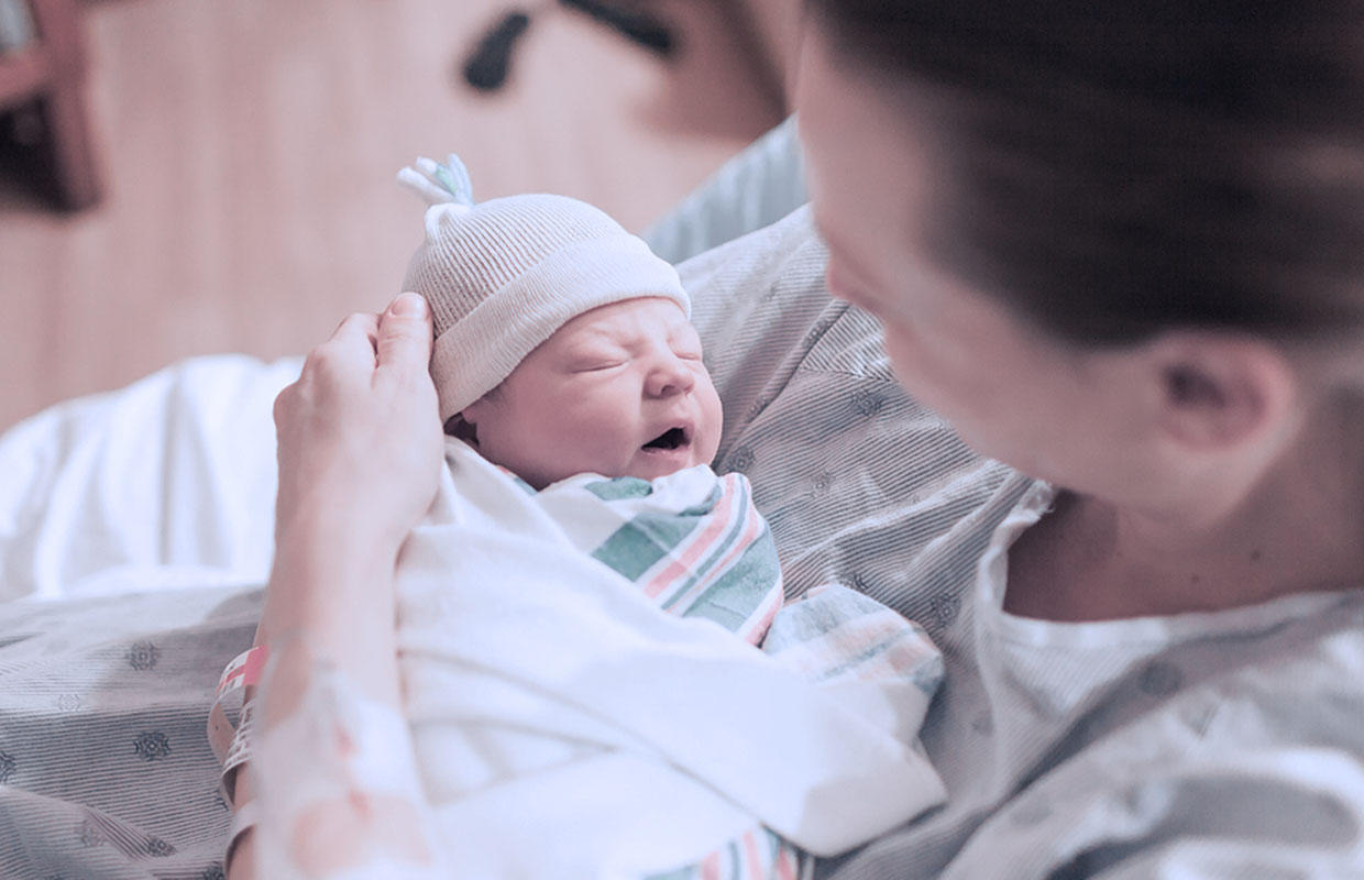 A young mother holds her newborn baby in the hospital.