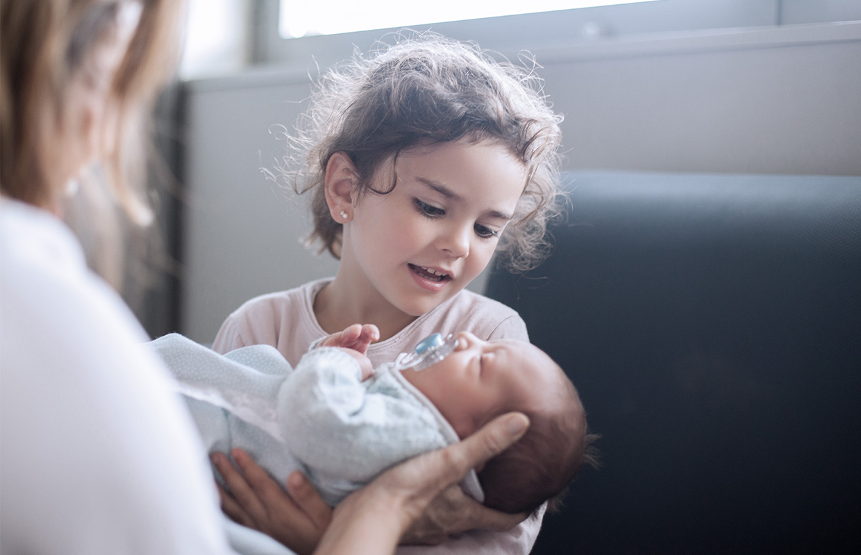 little girl holds her newborn sibling