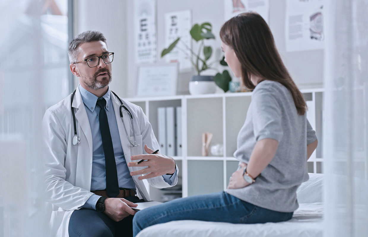 female patient sitting on an exam table talks to male physician