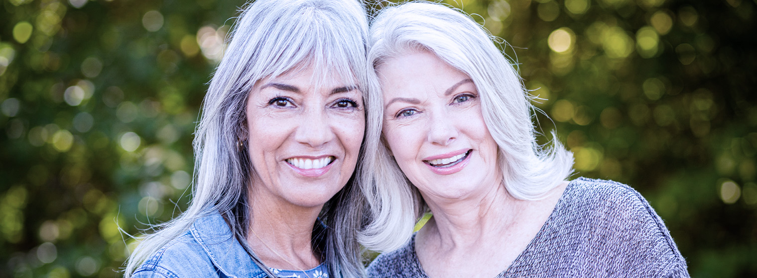 Two middle aged females smile and pose together.