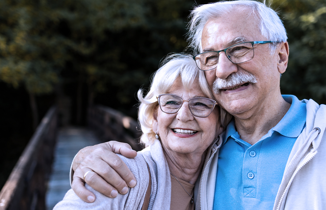 Senior couple hugs while enjoying the outdoors.