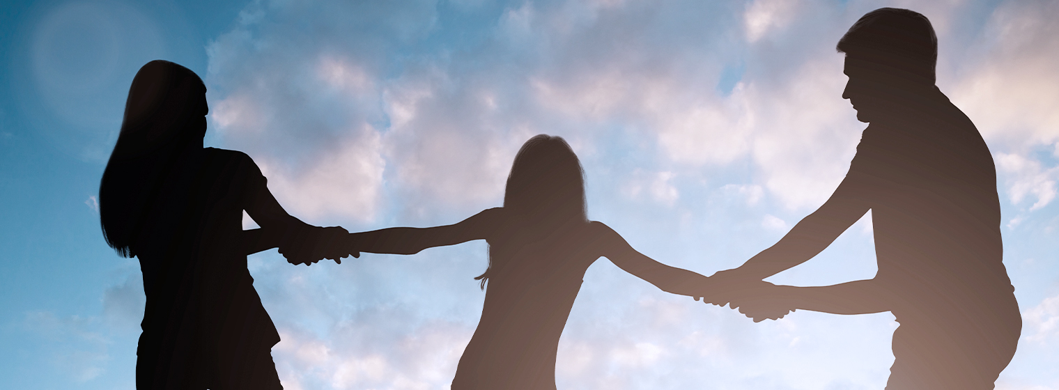 shadows of two parents tugging on the arms of a child