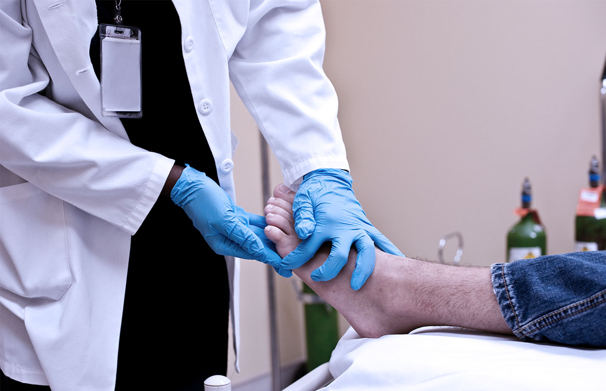 doctor in medical gloves touching patient's foot