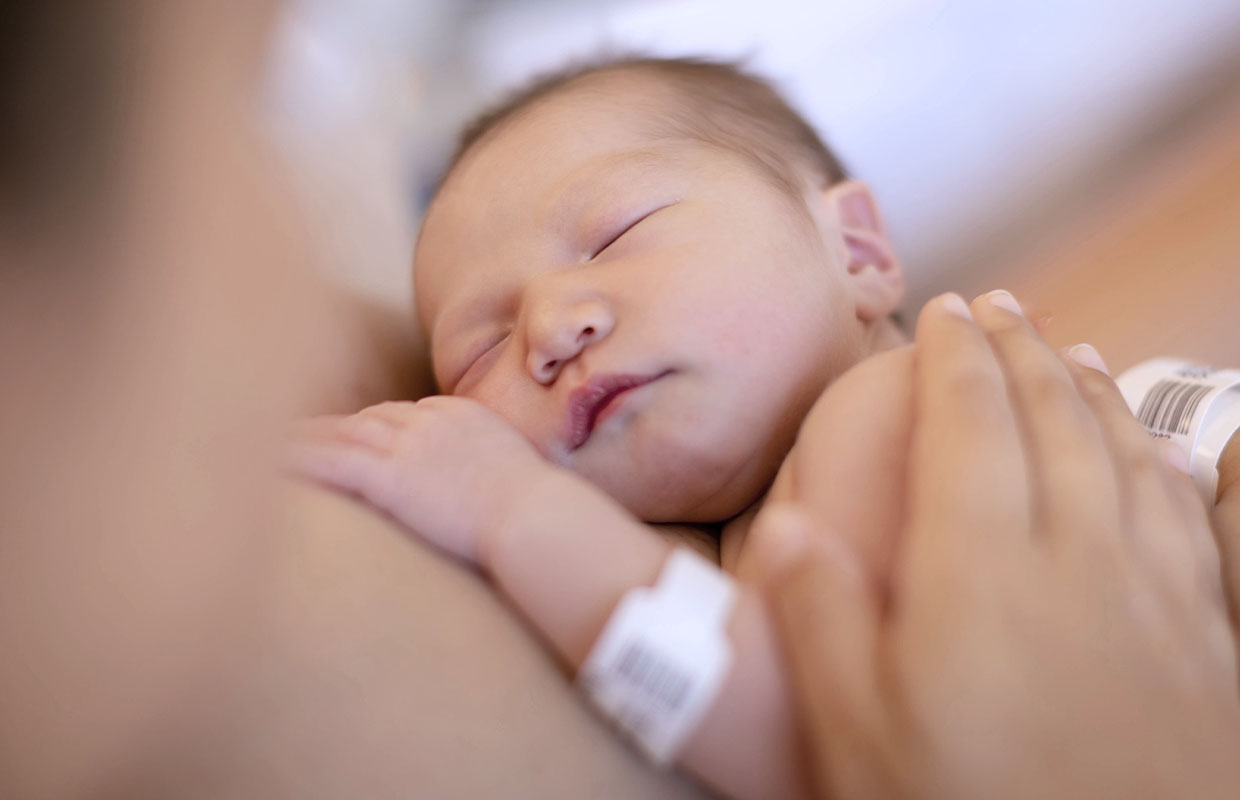 newborn resting on mother's chest with hospital bracelet