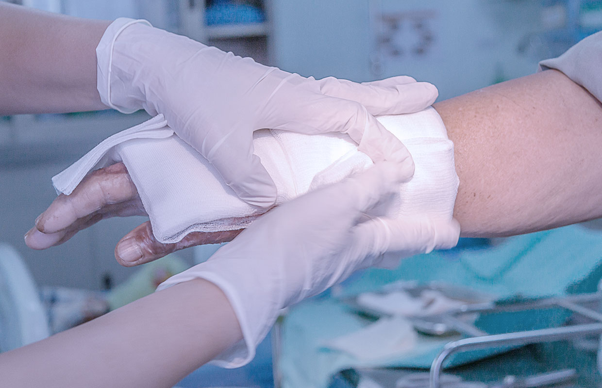 doctor in gloves wrapping the wrist of a patient in gauze