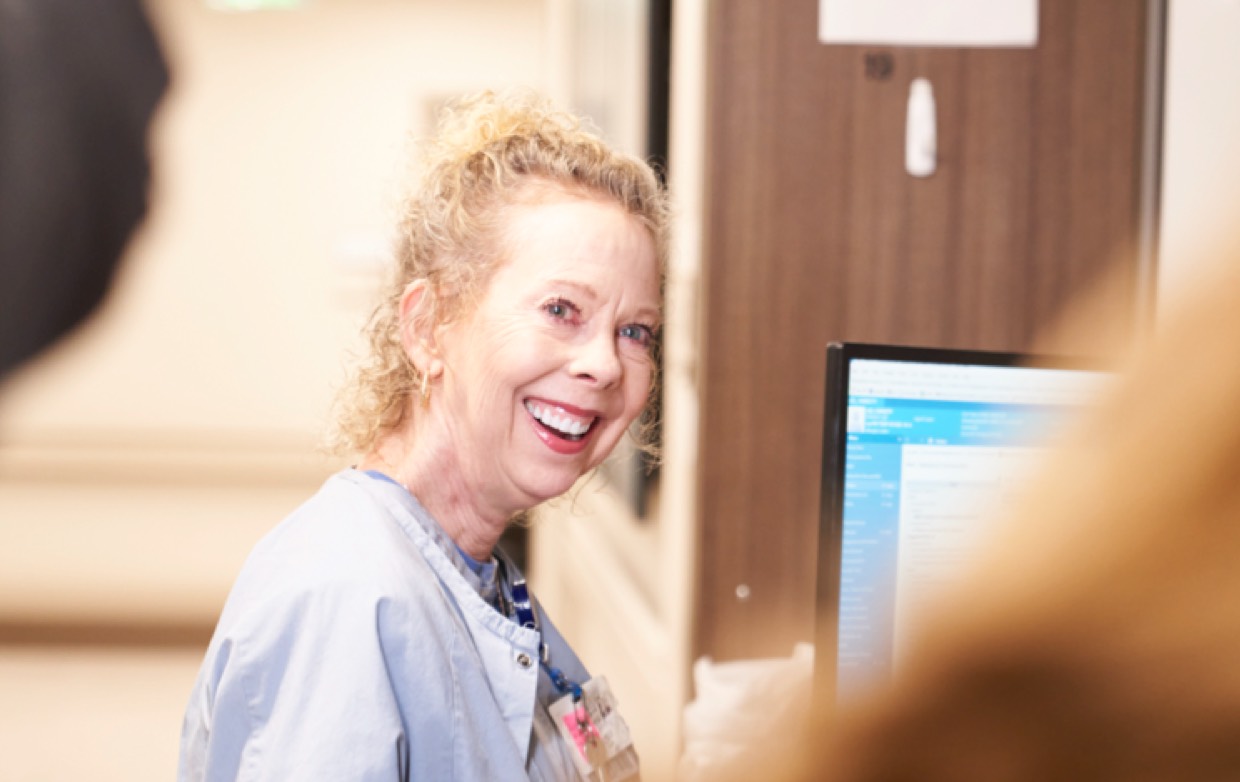 An elderly female nurse smiling while working.