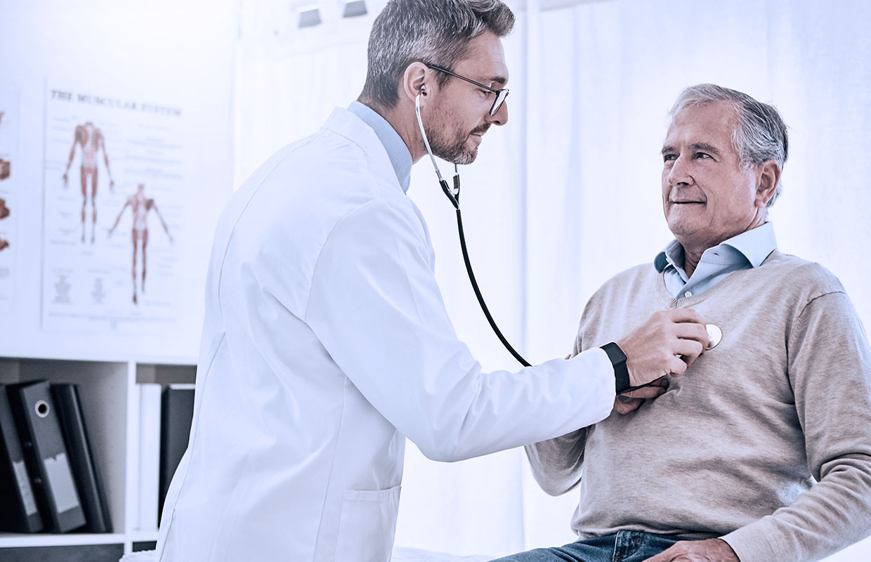 middle age male doctor listening to heartbeat of senior male patient