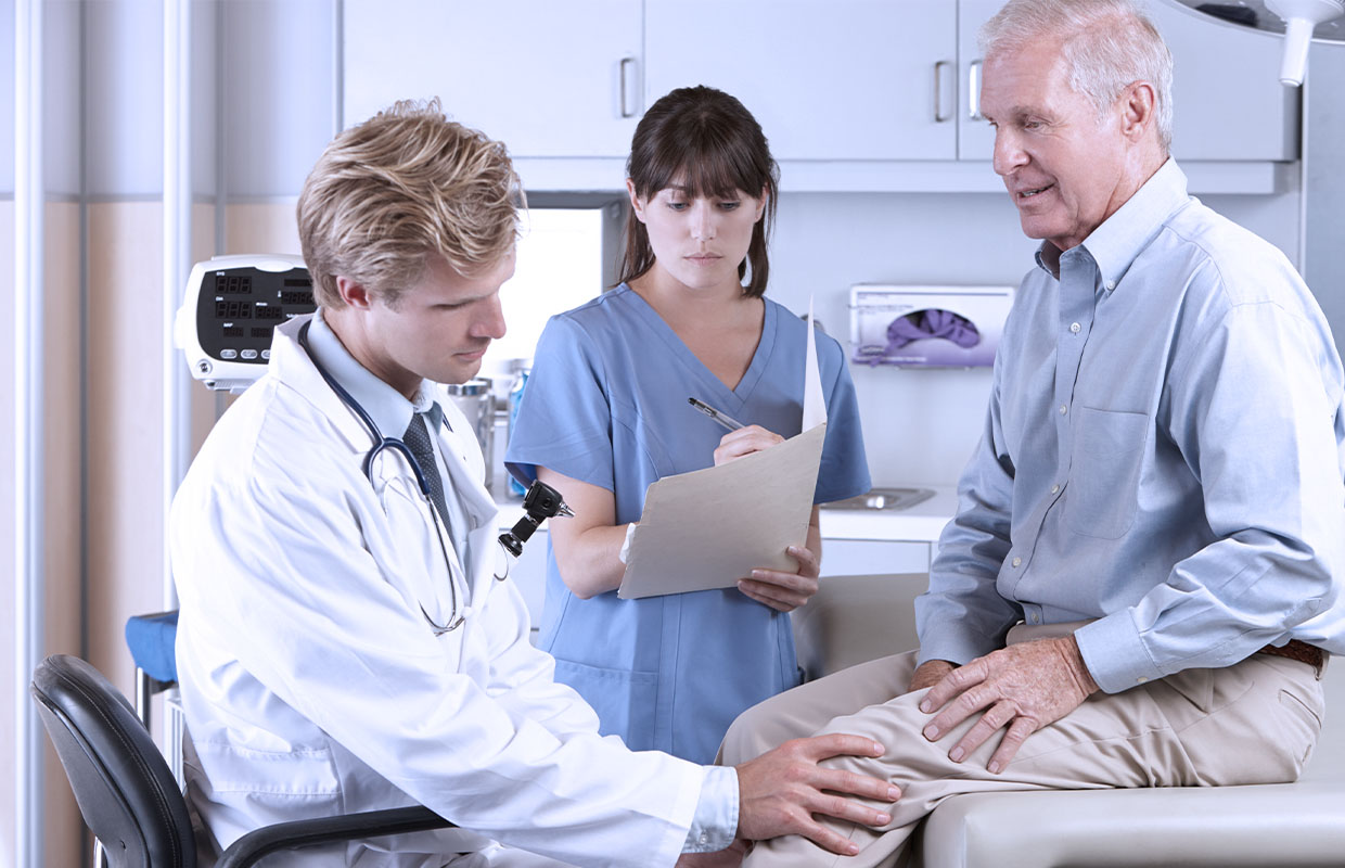 senior male patient getting knee examined by male doctor and female nurse