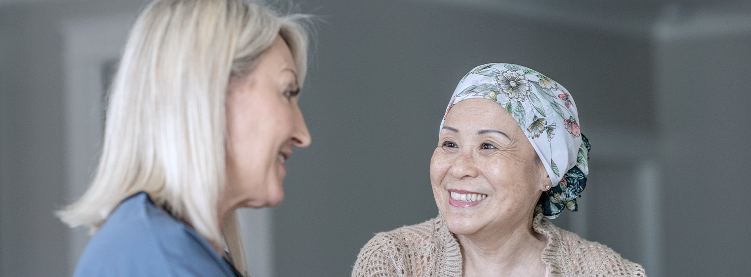 female nurse talks to female patient in hair wrap during chemo session