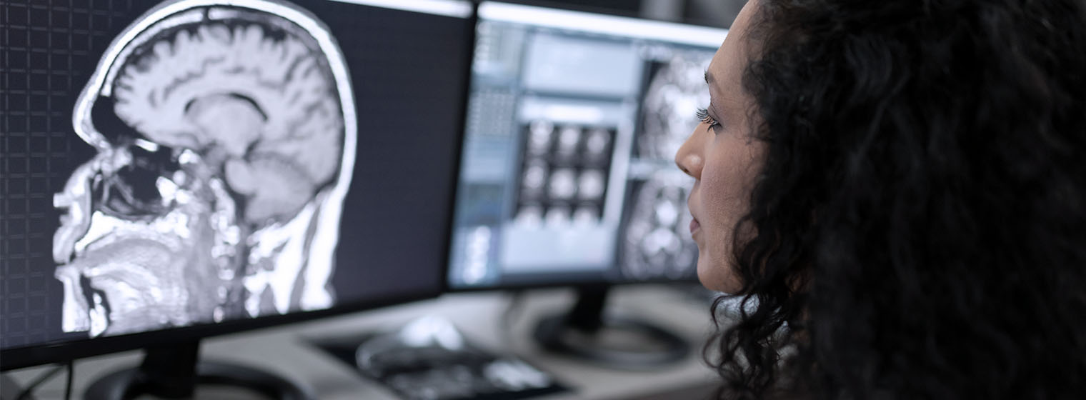 a neurosurgeon views an mri on a computer with multiple monitors