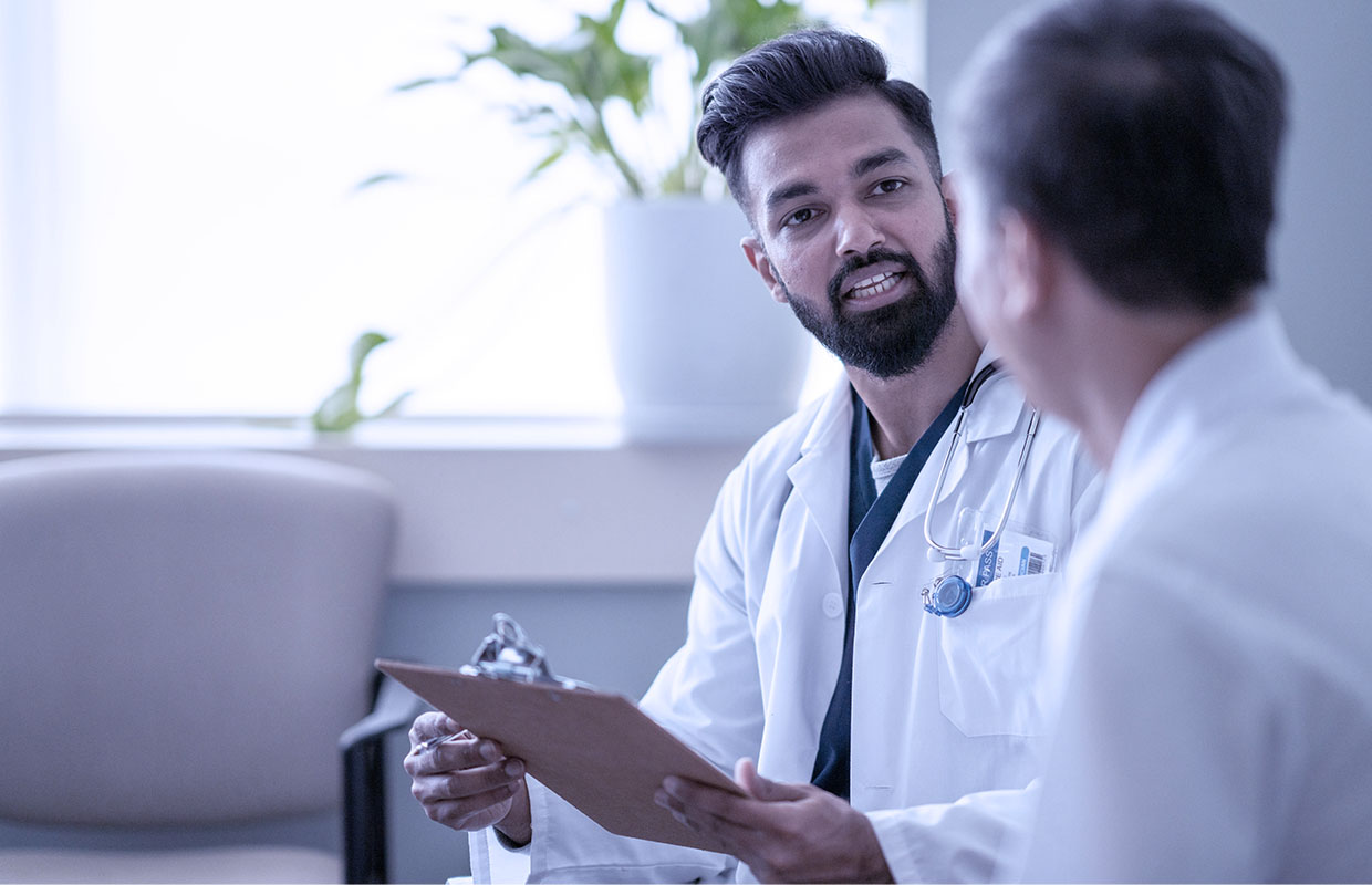 a doctor holds a clipboard and talks to another doctor