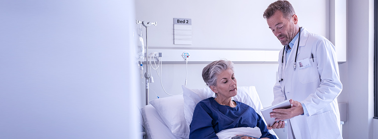 Male physician explains surgery results to female patient in the hospital.