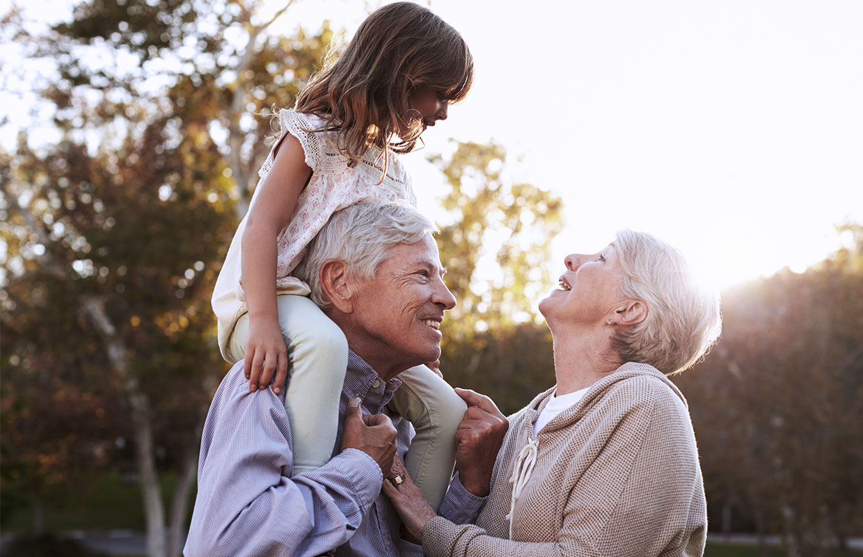 grandparents with young female child on grandpa's shoulder