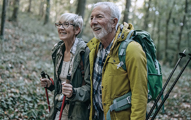 senior female and senior male hiking through the woods