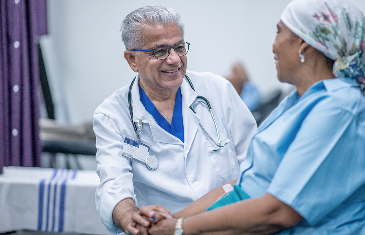 A doctor speaks with his cancer patient while she receives a chemotherapy treatment.