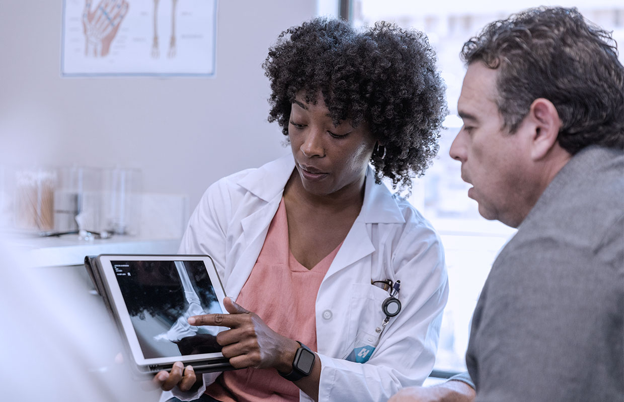 young female doctor shows xray of foot to middle aged male patient