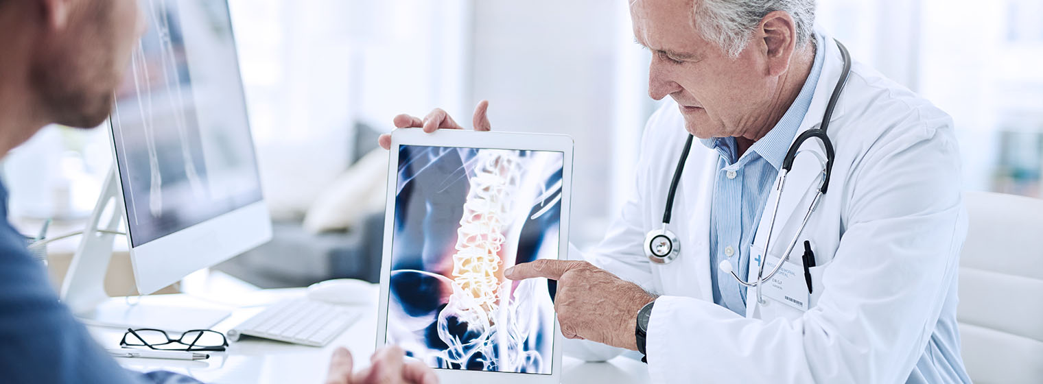 senior male doctor shows x-ray of spine to male patient