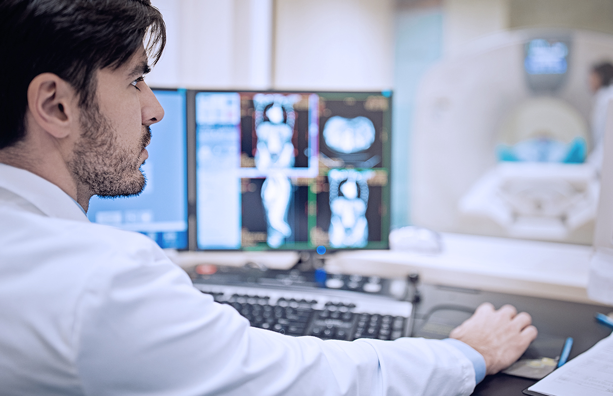 Expert cancer physician reviews CT scan on computer screen.