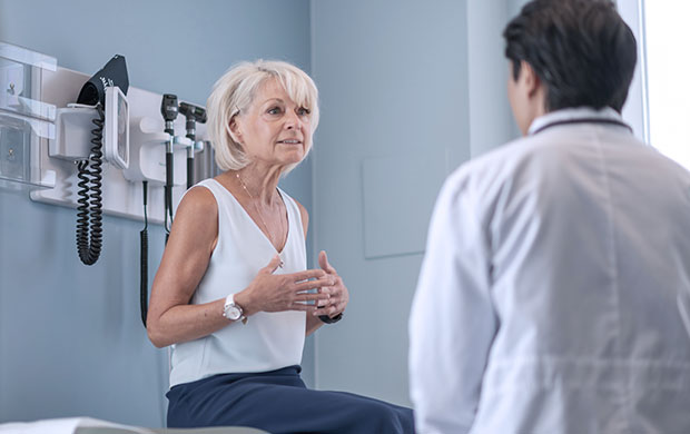 a woman sits on a medical table while talking to a doctor