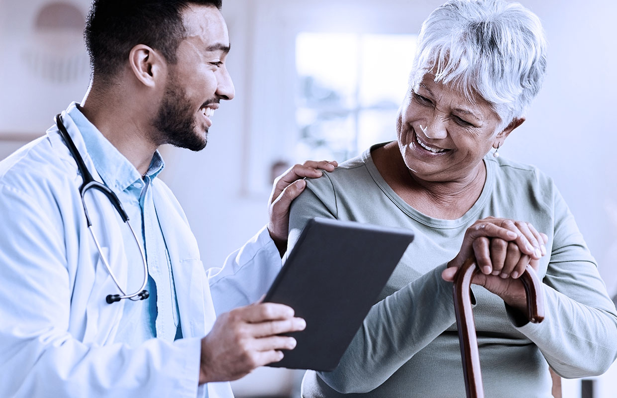 young male doctor laughs with senior female patient with cane