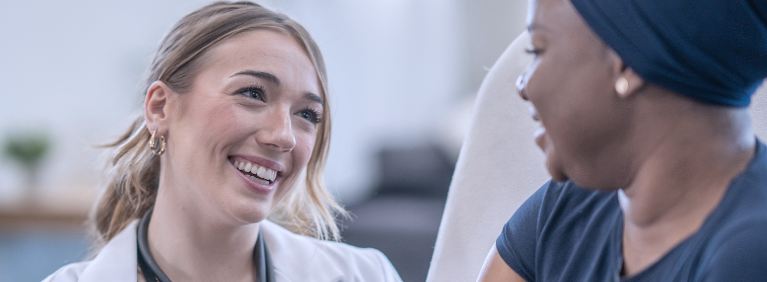 Female nurse practitioner speaks with cancer patient at a cancer center.