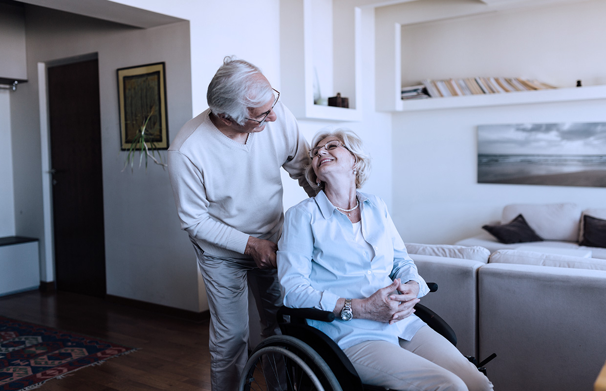 elderly woman in wheelchair looking up at elderly husband