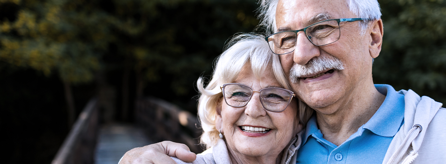 an older couple hugs each other and smiles for the camera