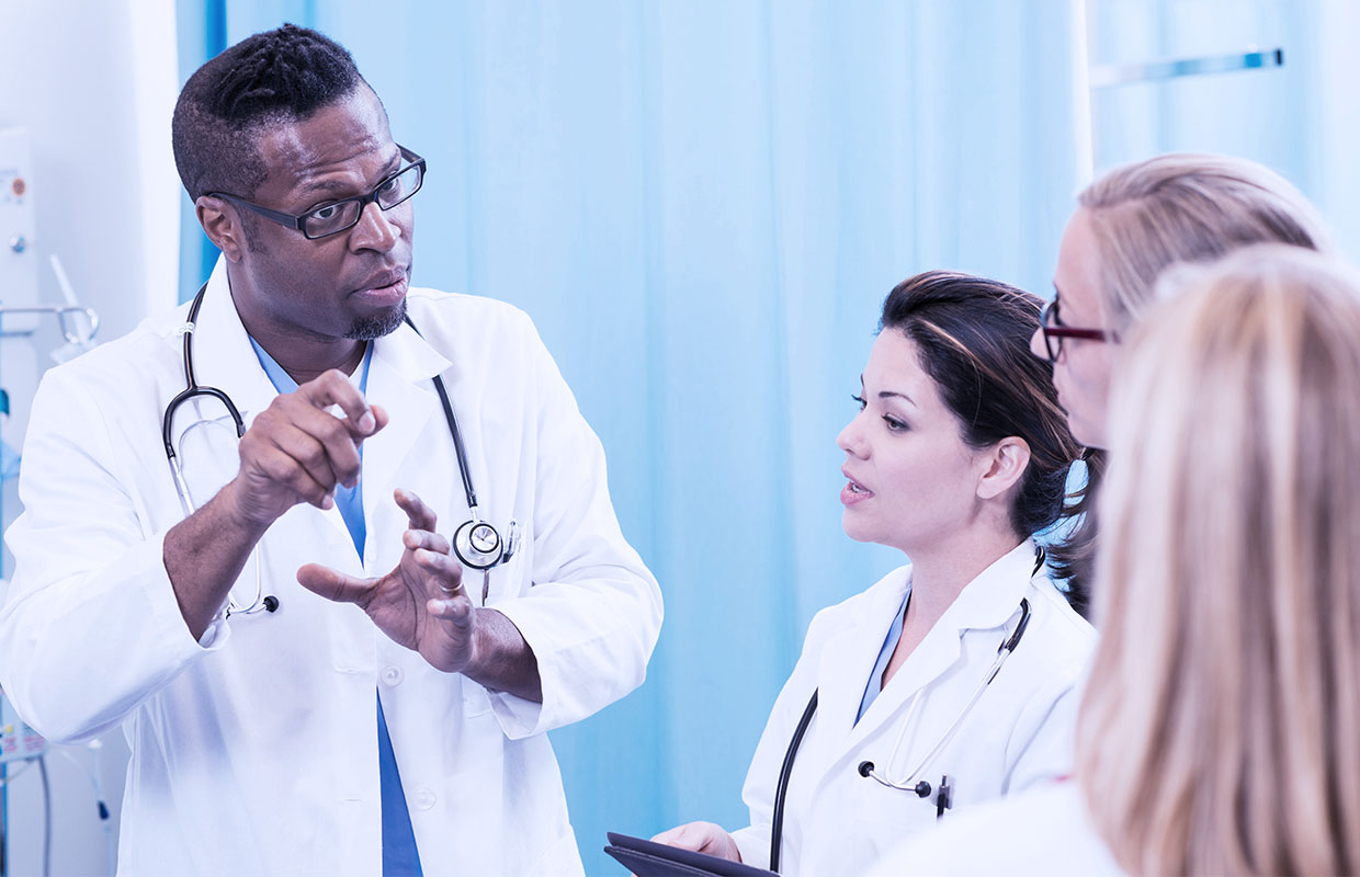 middle age male doctor teaching three medical students