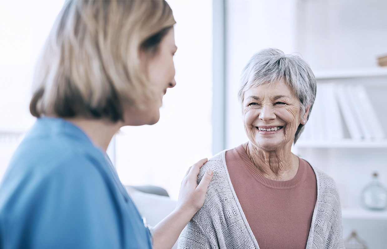 nurse in blue scrubs talking to senior woman in doctor's office