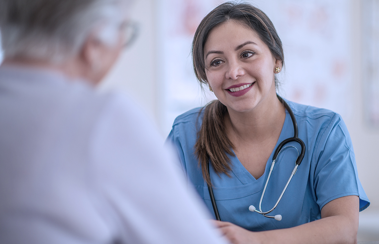 Oncology nurse talks to female cancer patient.