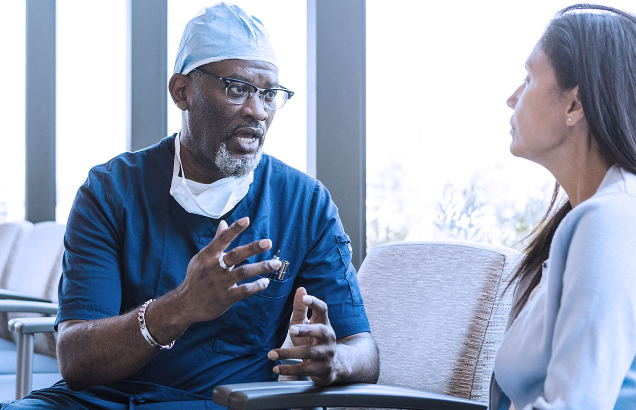 male middle-aged doctor in scrubs talking to female patient