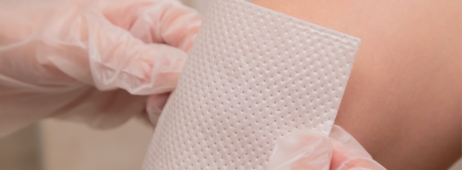 Closeup of a nurse's hand putting a bandage on a patient