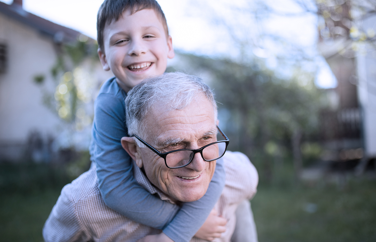 Grandfather plays outside with his grandchild.