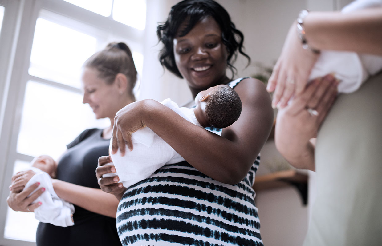 a pregnant woman in a new mom class holds a baby doll