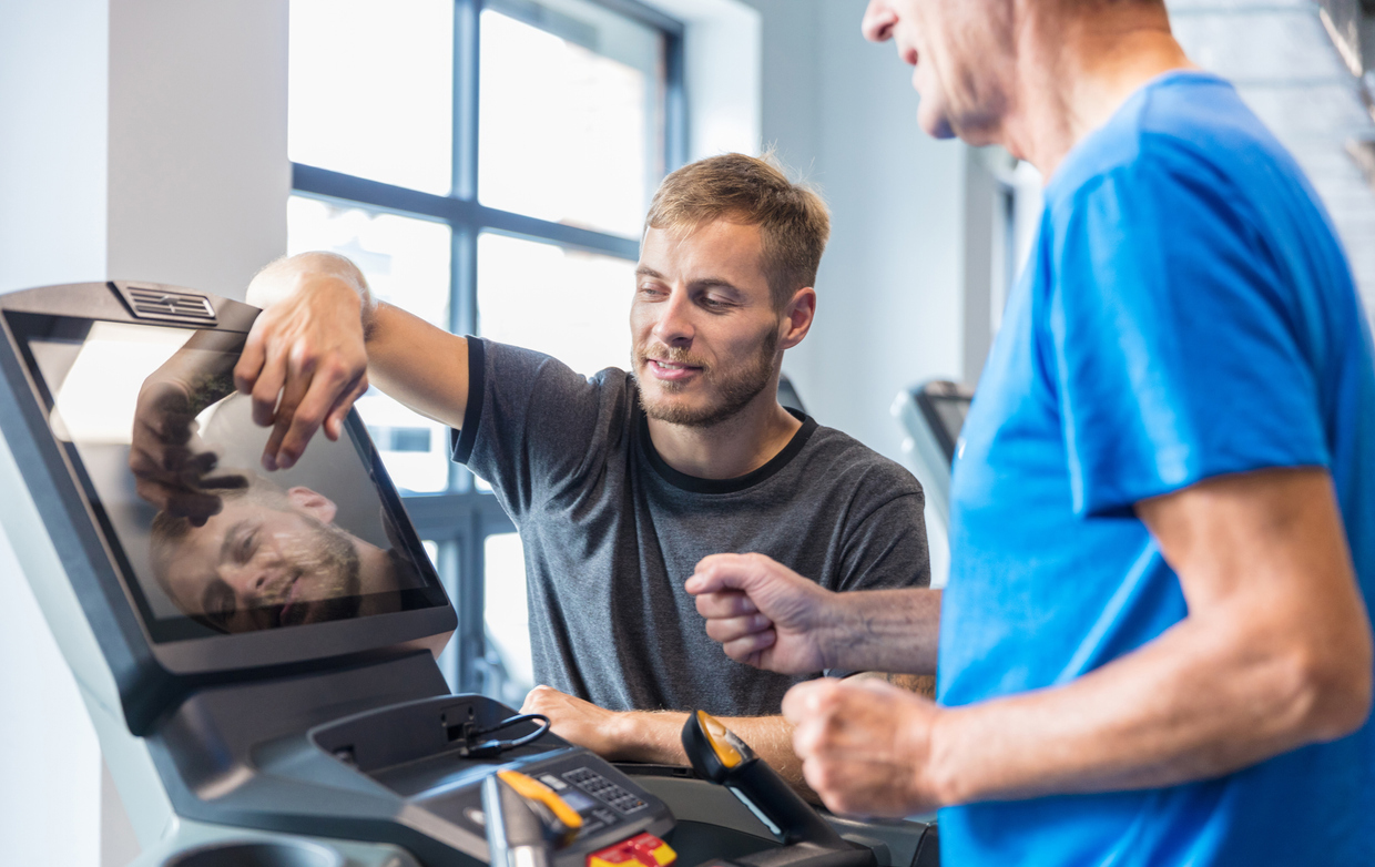 physical therapist working with elderly man on treadmill