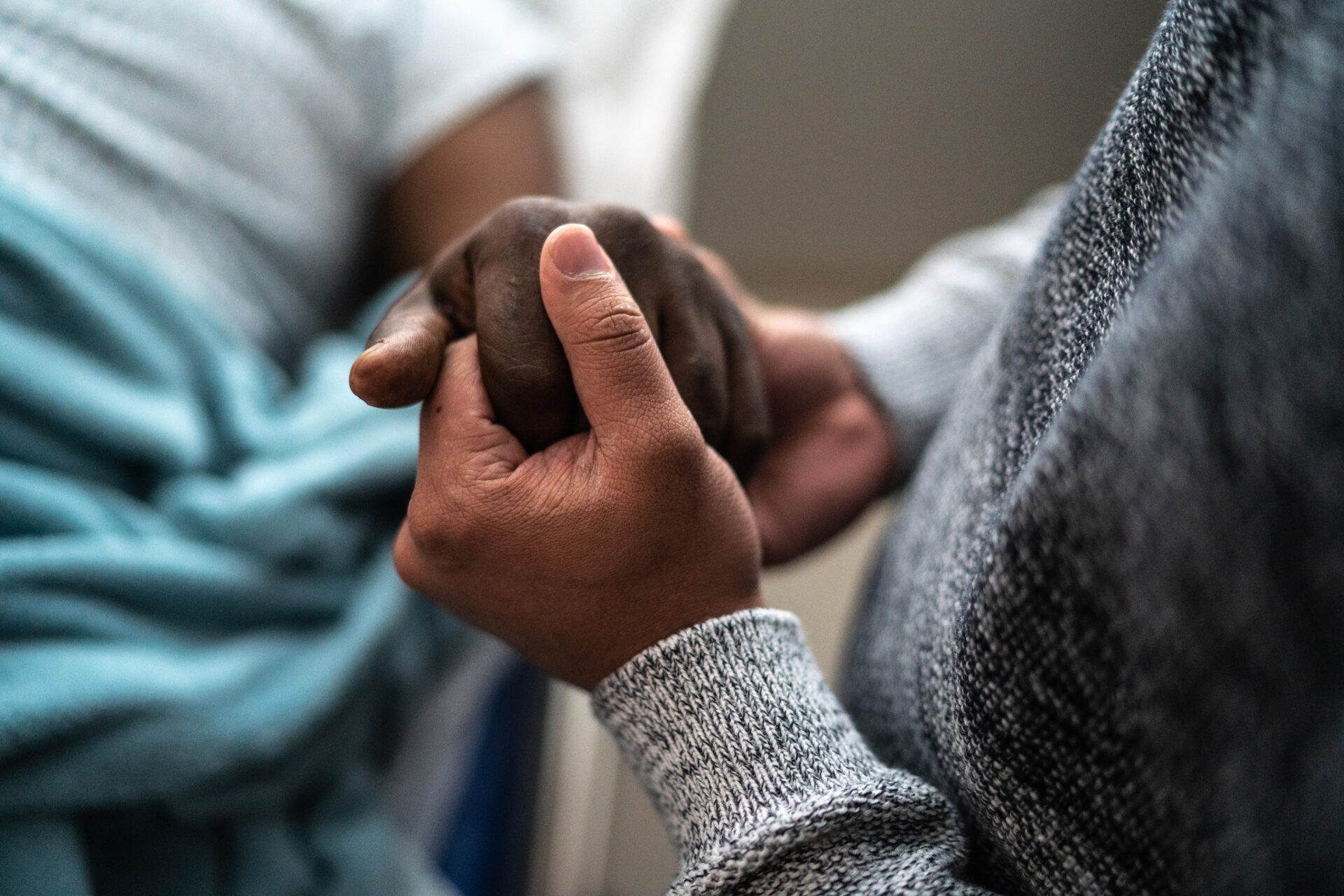 A person holds the hands of a patient in the hospital bed