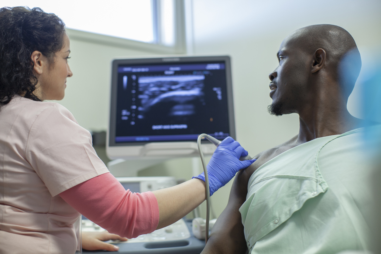 Nurse performing ultrasound on shoulder of patient in clinic