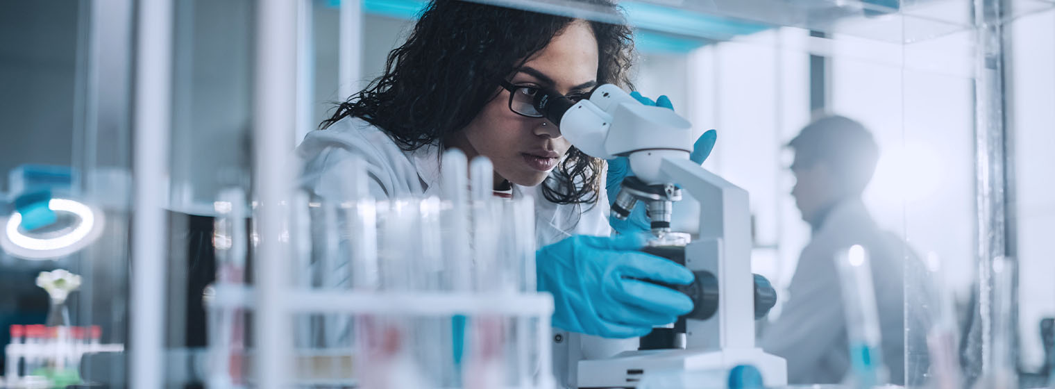 young female lab tech analyzes something in a microscope