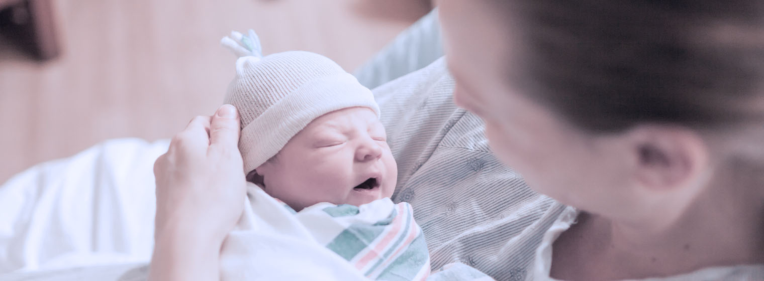 a mother holds a newborn baby wearing a cute hat