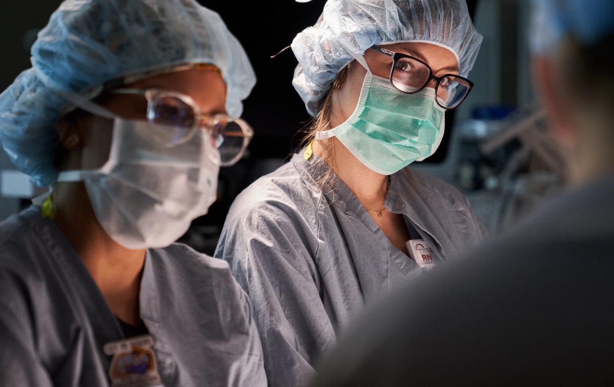 Two women surgeons looking at a doctor.