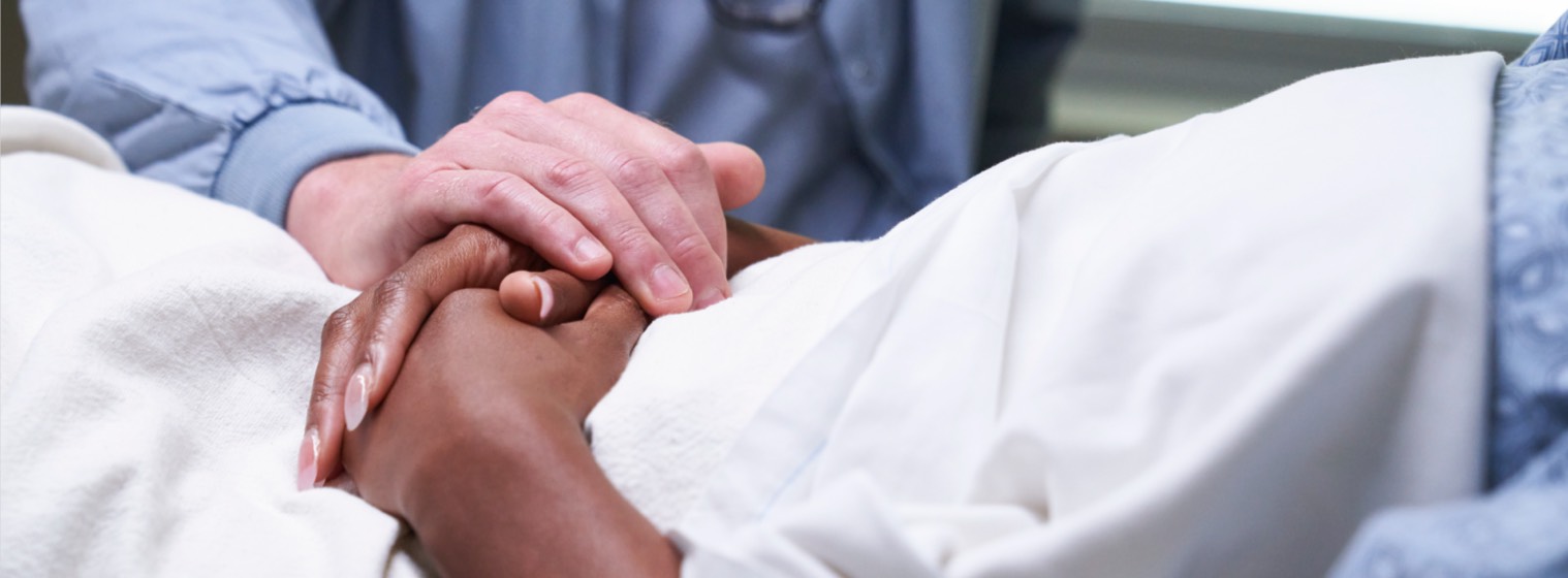 A nurse comforting a patient by patting their hand.