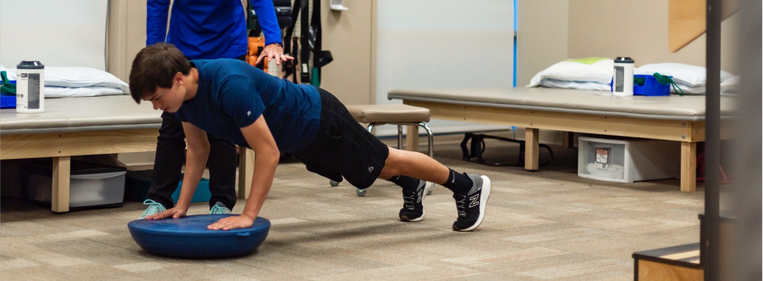 male patient doing a push up on a bosu in physical therapy