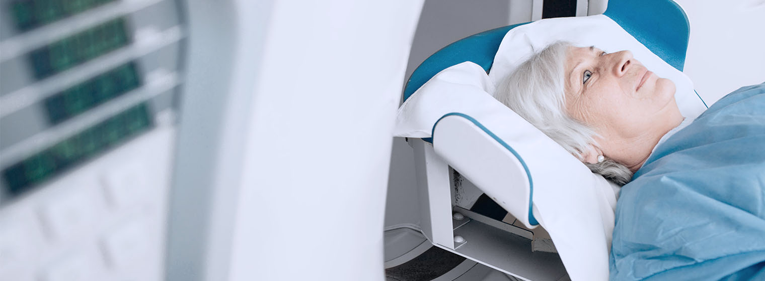 a woman lays on a CT scan machine and prepares to begin the sacn